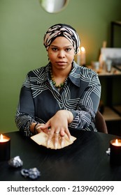 Vertical Portrait Of Black Young Woman Holding Tarot Cards And Looking At Camera In Fortune Tellers Shop