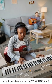 Vertical Portrait Of Black Young Woman Playing Music At Home And Wearing Headphones