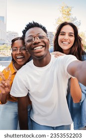 Vertical portrait of a group of multiracial young student people smiling taking a selfie together. Happy african american teenager laughing with his cheerful friends. Classmates on friendly meeting