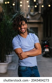 vertical portrait of an hispanic young man with dreadlocks. He is looking at camera and smiles