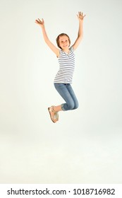 Vertical Portrait Of Jumping Little Girl. Cute Jumping Girl. Cheerful Pretty Young Girl Jumping And Holding Hands Up. - Shutterstock ID 1018716982