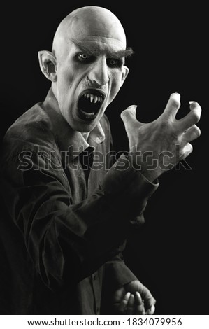 Vertical portrait of a man marked as a vampire on a black background.