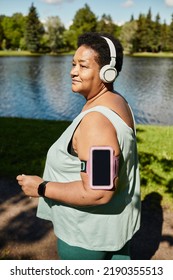 Vertical Portrait Of Mature Black Woman Running Outdoors And Wearing Headphones Enjoying Workout