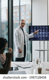 Vertical Portrait Of Mature Doctor Giving Presentation At Medical Conference And Pointing At X-ray Images