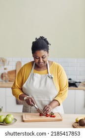 Vertical Portrait Of Smiling Black Woman Cooking Healthy Meal In Kitchen And Cutting Vegetables