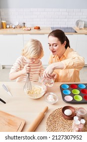 Vertical Portrait Of Smiling Young Woman Baking Cupcakes With Cute Little Boy Helping Mom