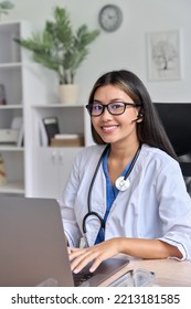 Vertical Portrait Of Successful Asian Young Female Therapist Doctor At Modern Workplace Using Laptop For Video Conference Chat With Patient During Virtual Consultation. Excellent Service, Online Visit