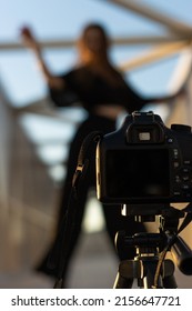 Vertical Portrait Of An Unrecognizable Dance Teacher Filming Herself With A Professional Camera On The Street To Teach Online Dance Classes. Selective Focus On The Camera With Tripod