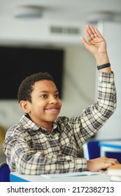 Vertical Portrait Of Young Black Boy Raising Hand In Class And Smiling Happily