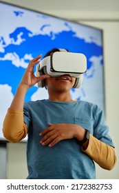 Vertical Portrait Of Young Black Boy Using VR In School Classroom With Geography Map In Background