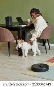 Vertical Portrait Of Young Black Woman Petting Dog While Working From Home In Modern Apartment