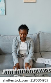 Vertical Portrait Of Young Black Woman Playing Synthesizer At Home And Composing Music In Minimal Home Setting, Copy Space