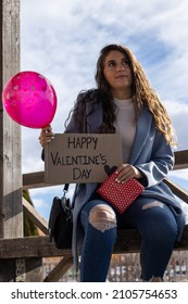 Vertical Portrait Of A Young Woman With A Happy Valentine's Day Sign,gift And Love Balloon Waiting For His Partner To Surprise Him And Celebrate Valentine's Day.