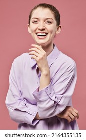 Vertical Portrait Of Young Woman Laughing Against Pink Background In Studio