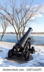 Vertical Rear View Of An Old Cannon On The Sillery Belvedere, With The St. Lawrence River And The South Shore Seen In The Background During An Early Winter Afternoon, Quebec City, Quebec, Canada
