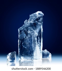 Vertical Rectangular Block Of Ice With A Broken-off Top Isolated On A Dark Blue Background With Clipping Path.