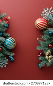 Vertical red Christmas background with snow-dusted pine branches and ornaments