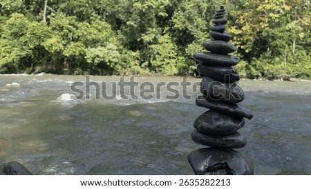 Vertical river stone stack in serene nature setting, reflecting inner peace, stability, and harmony—perfect visual for yoga, mindfulness, or eco retreat branding.