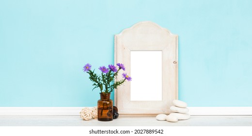 Vertical Rustic Wooden Picture Frame With Matte And Purple Daisies In Apothecary Bottle In Front Of Turquoise Wall. Blank Image Area Isolated With Clipping Path. Banner Shaped  Mockup. 