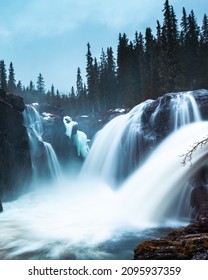 A Vertical Scenic View Of A Waterfall Stream In A Motion At The Pine Forest