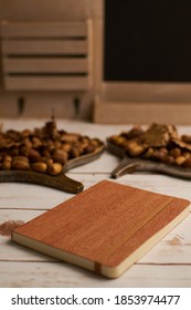 A Vertical Selective Focus Shot Of A Journal And Acorns On Boards