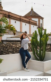 A Vertical Shallow Focus Of A Caucasian Young Woman With A Hat Posing On A Rooftop