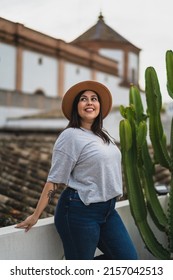 A Vertical Shallow Focus Of A Caucasian Young Woman With A Hat Posing On A Rooftop