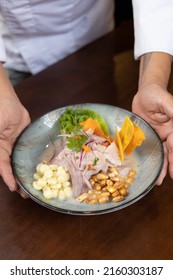 A vertical shoot of a hand of chef pushing a plate of ceviche - Shutterstock ID 2160303187