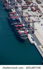Vertical shot of the aerial view of a container ship anchored at a commercial dock.