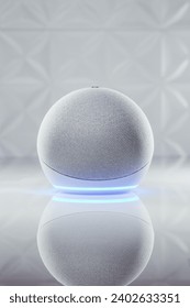A vertical shot of Amazon Echo 4 with neon blue led light on the bottom part on the white table in background of shiny white textured walls