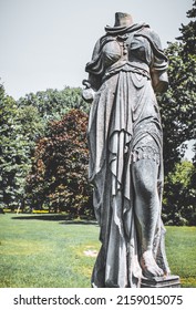 A Vertical Shot Of An Ancient Broken Statue In The Park 