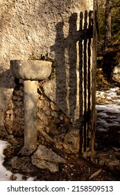 A Vertical Shot Of An Ancient Stone Holy Water Font Outdoors Under The Sunlight