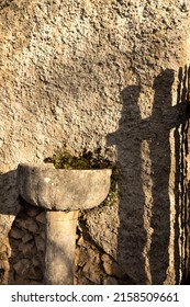 A Vertical Shot Of An Ancient Stone Holy Water Font Outdoors Under The Sunlight