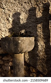 A Vertical Shot Of An Ancient Stone Holy Water Font Outdoors Under The Sunlight