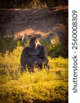 A vertical shot of an ape sitting in the middle of a grassy field