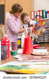 Vertical Shot Of An Art Teacher And A Middle School Student Looking At A Painting During An Art Class.