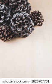 A vertical shot of assorted decorative pine cones on a light brown surface