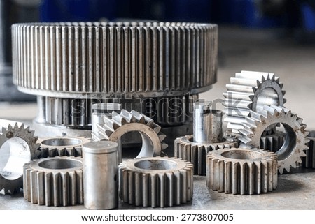 ​A vertical shot of an automatic transmission planetary gear carrier and several steel cogwheels on a workshop floor.