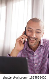 Vertical Shot Of Bearded Bald Executive Looking Man Making A Phonecall Smiling. People Using Smartphone With Negative Space.