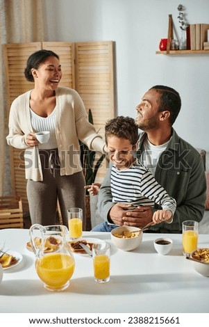 vertical shot of beautiful joyous african american family laughing and having good time at breakfast