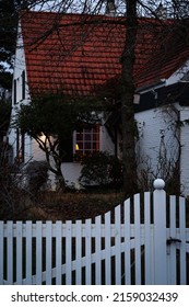 A Vertical Shot Of A Beautiful White Painted Brick House Behind A Fence