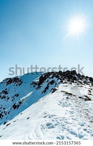 Vertical shot from below the top of snow-capped Provincia mountain with sun lens flare, Chile