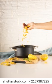 A Vertical Shot Of The Black Pot And The Hand Tossing Pasta In The White Decorated Kitchen