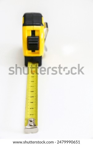 Vertical shot of black and white retractable tape measure against white background, selective focus, measuring length, width and height concept, accuracy and precision