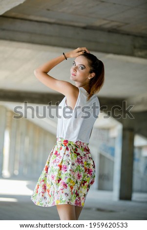 A vertical shot of a blonde Bosnian woman with a ponytail in a skirt