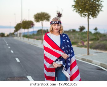 A Vertical Shot Of A Blonde Caucasian Woman From Spain Covered In The American Flag And Wearing A USA Headband