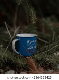 A vertical shot of a blue mug with an inspiration quote about dreams in a forest - Shutterstock ID 2364323425