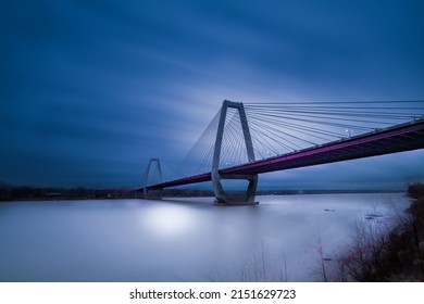 A Vertical shot of a bridge over the water during evening and a blue cloudy sky on the horizon - Powered by Shutterstock