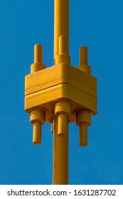 A Vertical Shot Of A Brightly Colored Yellow Metal Contraption With A Pure Blue Background