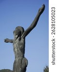 A vertical shot of a bronze crucified Christ outside the Church of St. James the Apostle with the cross on Cross Hill in Medjugorje, Bosnia and Herzegovina.